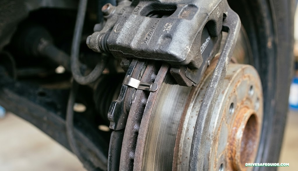 Close-up of a brake caliper showing a brake pad wear indicator tab against a disc rotor
