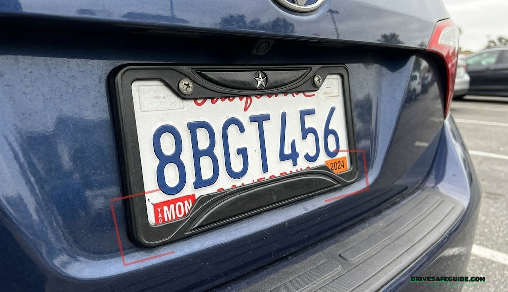 Close-up of a rear vehicle license plate partially covered by a decorative frame, illustrating a plate visibility violation