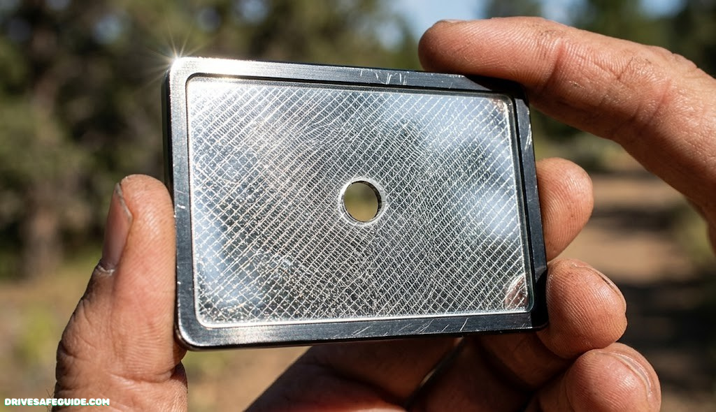 Close-up of a signal mirror with a sighting hole and retroreflective mesh grid