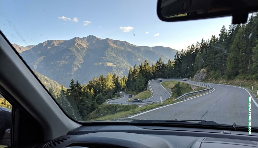 Winding mountain road seen through a car windshield, a common trigger for motion sickness while driving